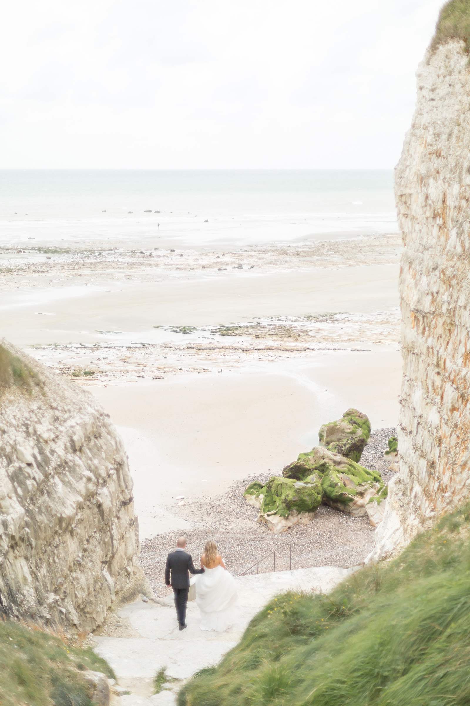 photographie de mariage. les mariées descendent les marches pour accéder à la plage de la falaise de vasterival 